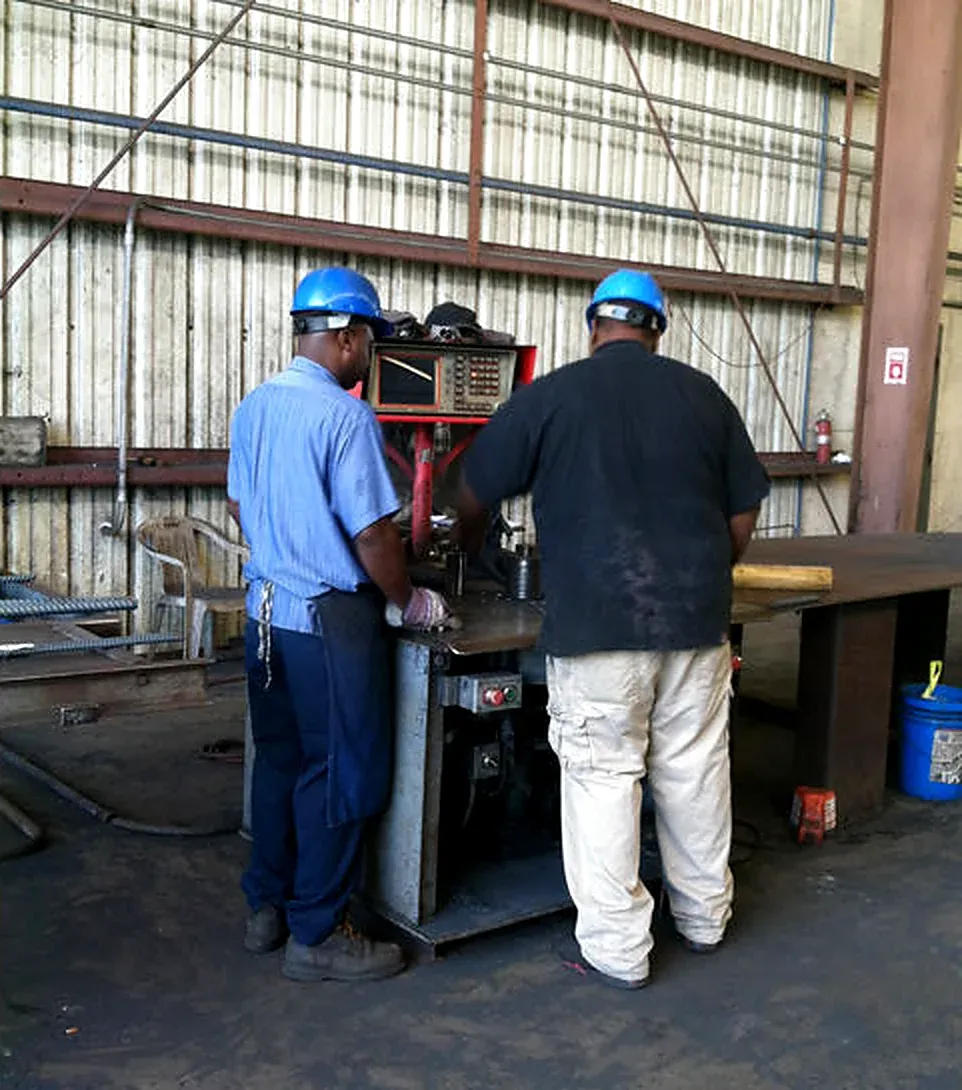 Two workers in hard hats at a reinforcing steel machine